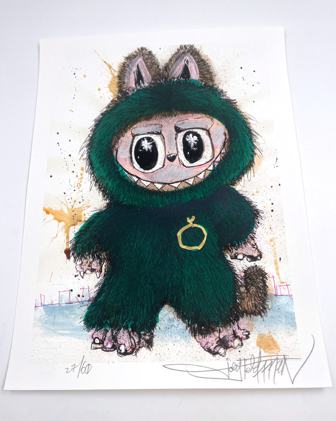 A whimsical Joey Feldman illustration of a furry, wide-eyed creature in a green cat-eared costume with a gold ring necklace, set on a white background with ink splatters, colorful accents, and hand-painted details.