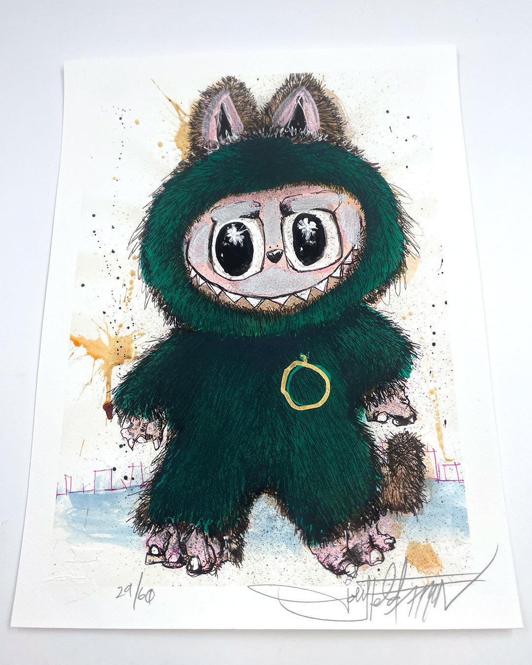 A green, bunny-eared creature with a gold ring on its chest stands on white paper. This archival pigment print by Joey Feldman features hand-painted details and is signed and numbered.
