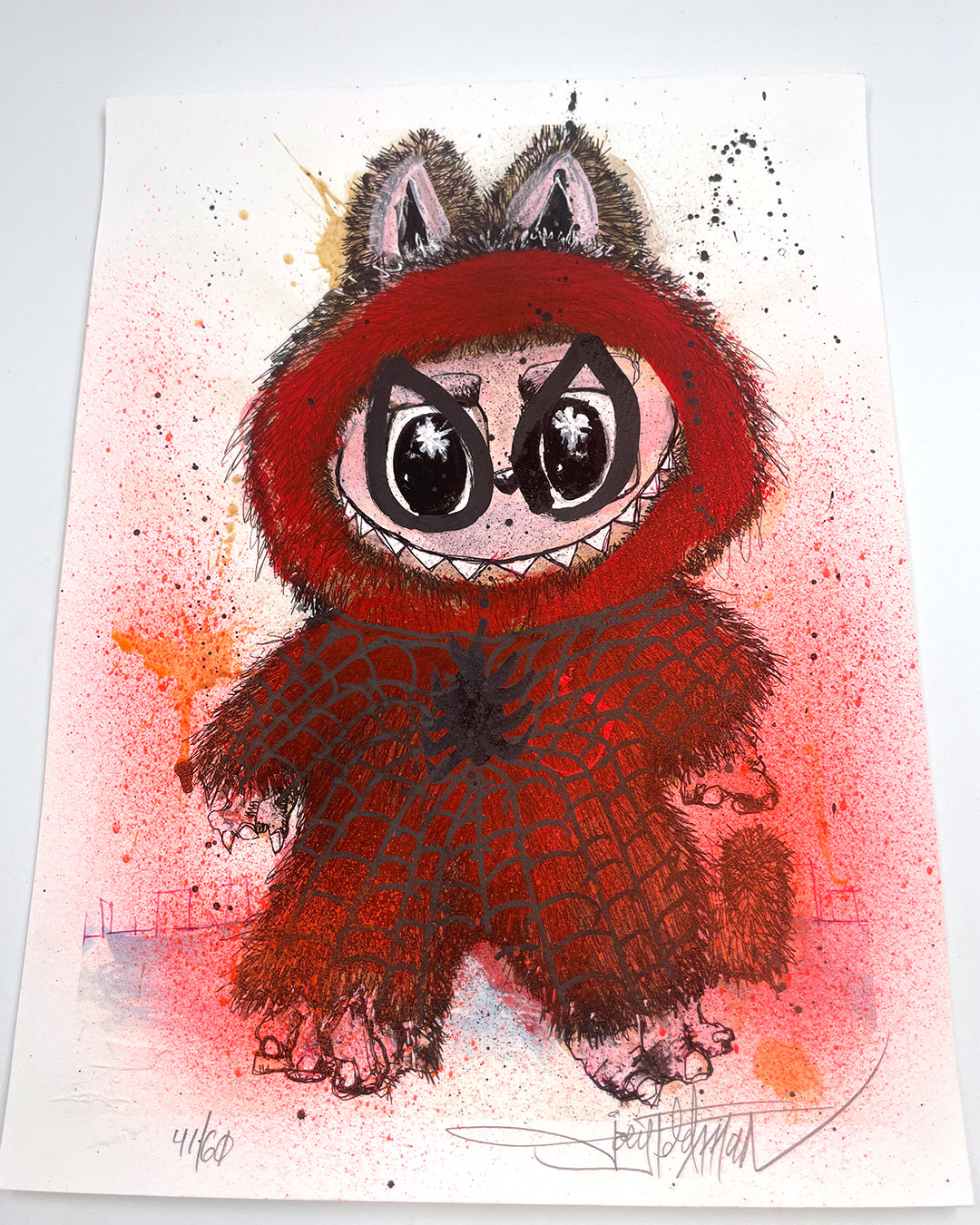A whimsical Joey Feldman-inspired illustration shows a wide-eyed creature in a red furry hood and Spider-Man-style costume, with animal ears and sharp teeth, set against a vibrant splattered red-orange background.