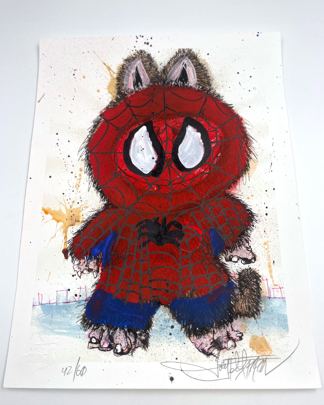 A whimsical Joey Feldman print features a furry raccoon in a Spider-Man costume upright on a white background with paint splatters. This archival pigment print is signed and numbered 42/60 in the bottom left corner.