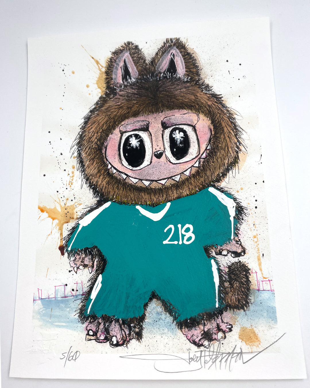 A cartoon character with big eyes, a wolf-like hood, sharp teeth, and a green tracksuit labeled 218 is set on a splattered background in this signed and numbered Joey Feldman archival pigment print.