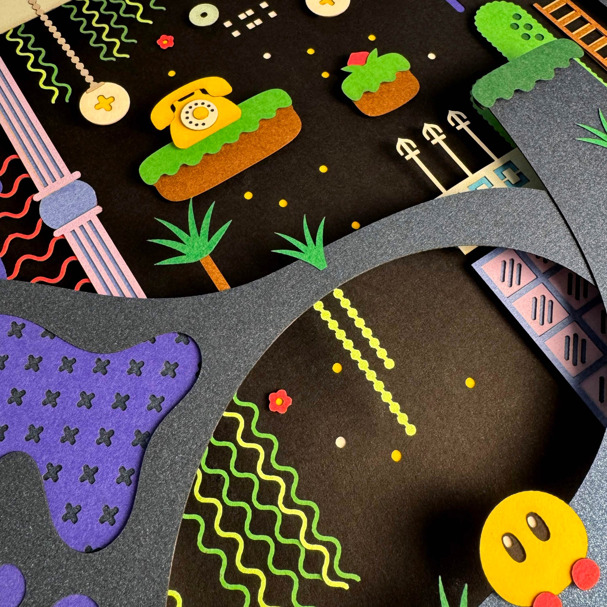 A playful collage by Michelle Romo features layered cut paper inspired by Animal Well—a retro game scene with floating platforms, stylized plants, dotted lines, a yellow phone, and a smiling yellow character set against a dark background.