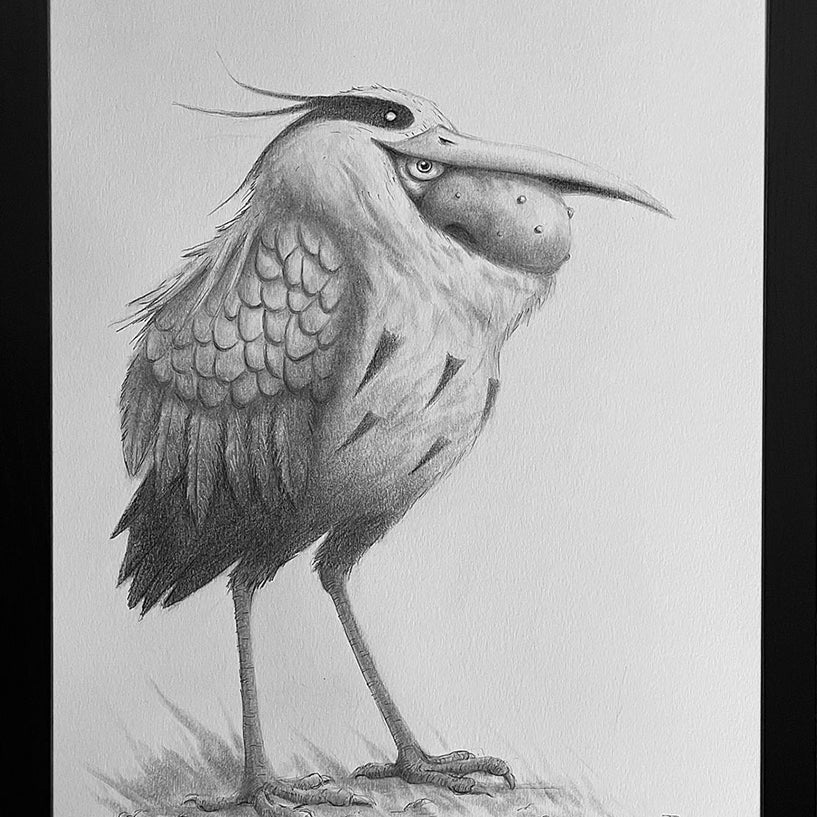 Graphite artwork by Ruel Pascual, framed in black by Spoke Art, features a whimsical, bird-like creature with shaggy feathers, long legs, expressive eyes, and a large beak reminiscent of a Grey Man Heron.