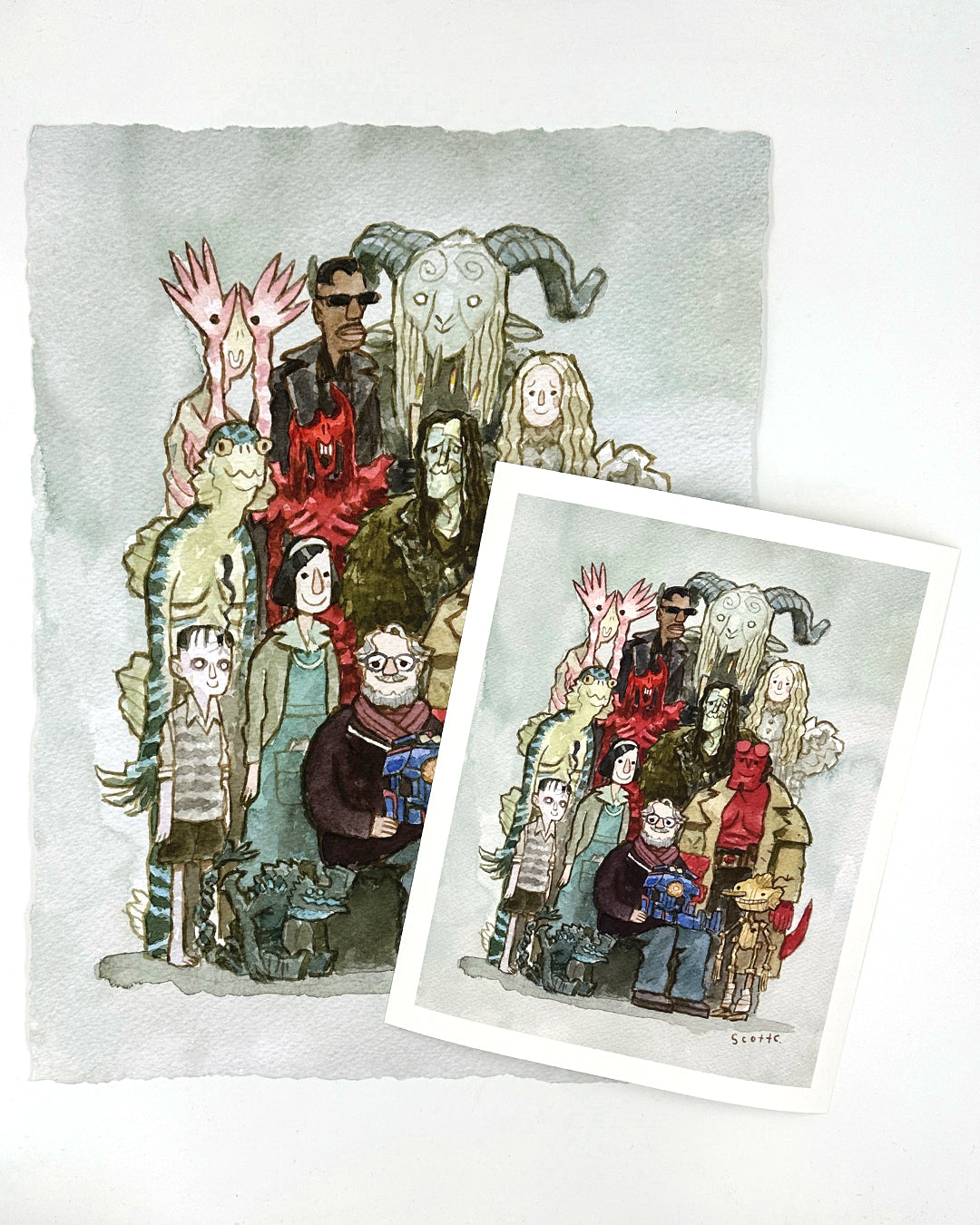 A watercolor illustration by Scott C. shows quirky monster and human characters posing for a group photo. The limited edition "Gathering Around Guillermo" print rests atop the original art.