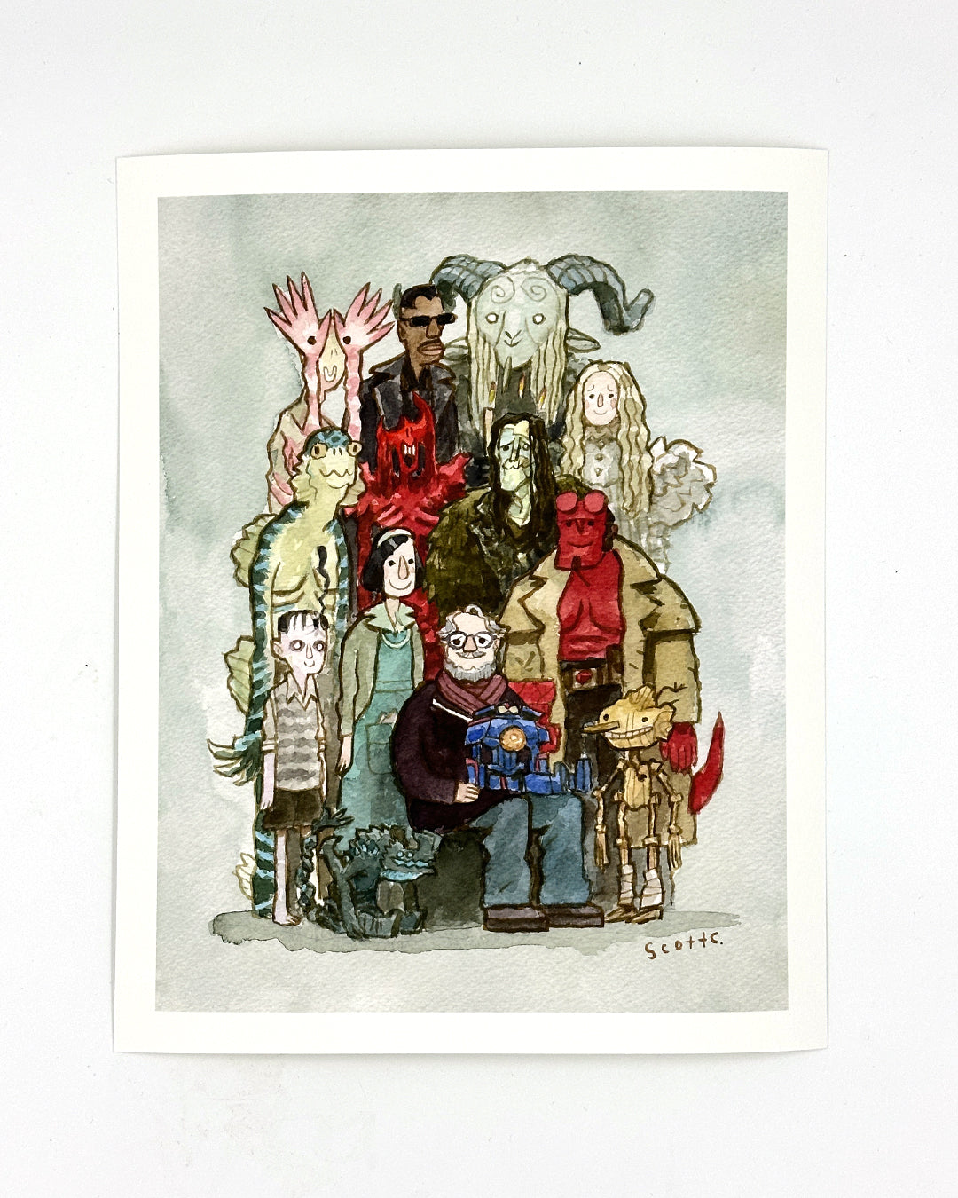Scott C.’s “Gathering Around Guillermo” is a whimsical watercolor illustration print depicting Guillermo del Toro with a red demon, amphibian man, and faun—an ideal limited edition art collectible.