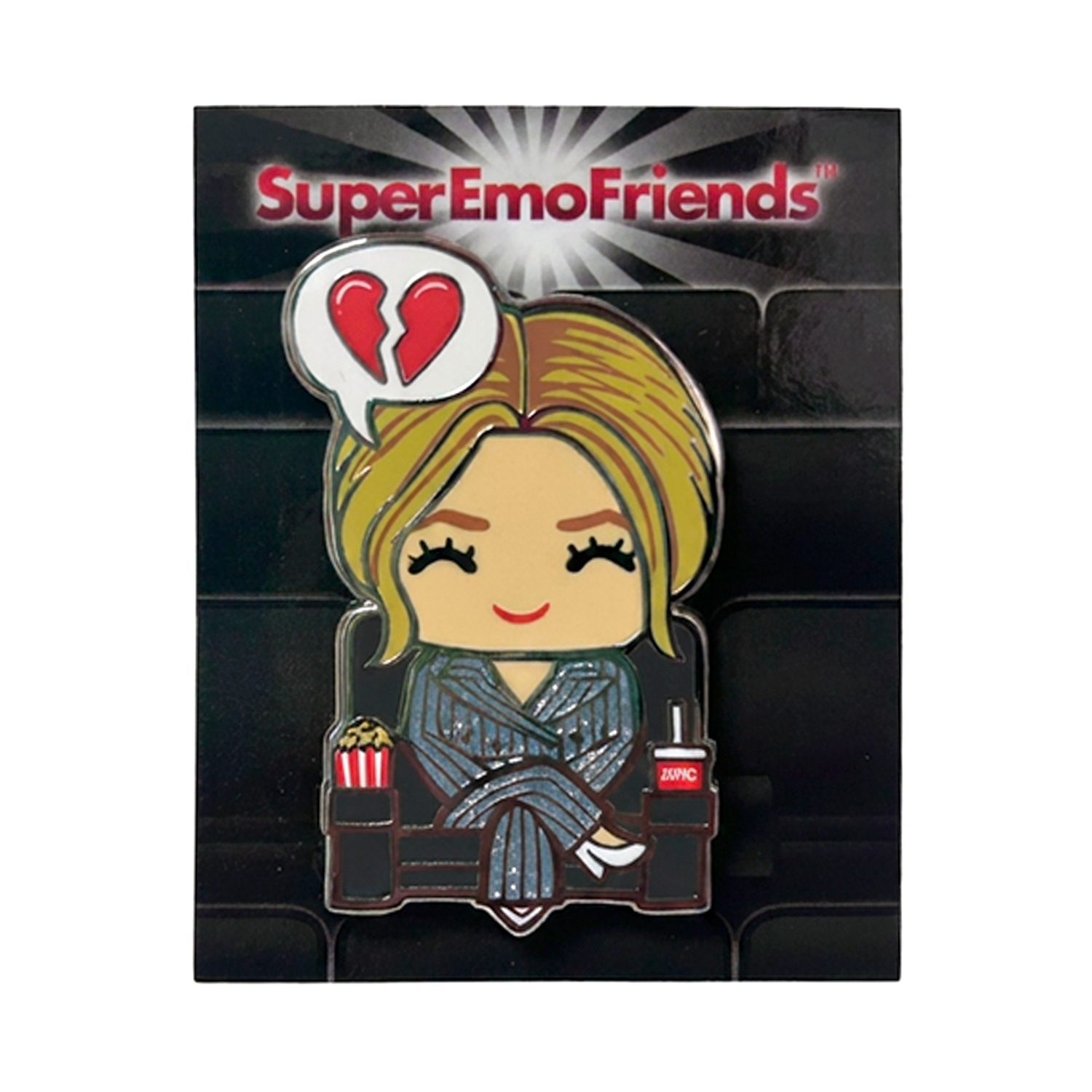 This limited edition Super Emo Friends hard enamel pin shows a cartoon woman in striped pajamas with popcorn, dreaming of a broken heart. The background displays “Super Emo Friends” with a vibrant burst design.