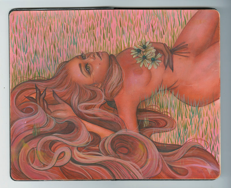 painting in an open face Moleskine notebook of a red nude woman with long hair aying in the grass holding flowers against her chest by artist Tatiana Suarez