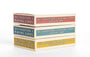 Three boxes labeled Max Dalton Wes Anderson playing cards, volumes one, two, and three, stacked on a white surface. Featuring artwork by Max Dalton, these custom-designed playing cards come in vibrant red, blue, and yellow boxes.