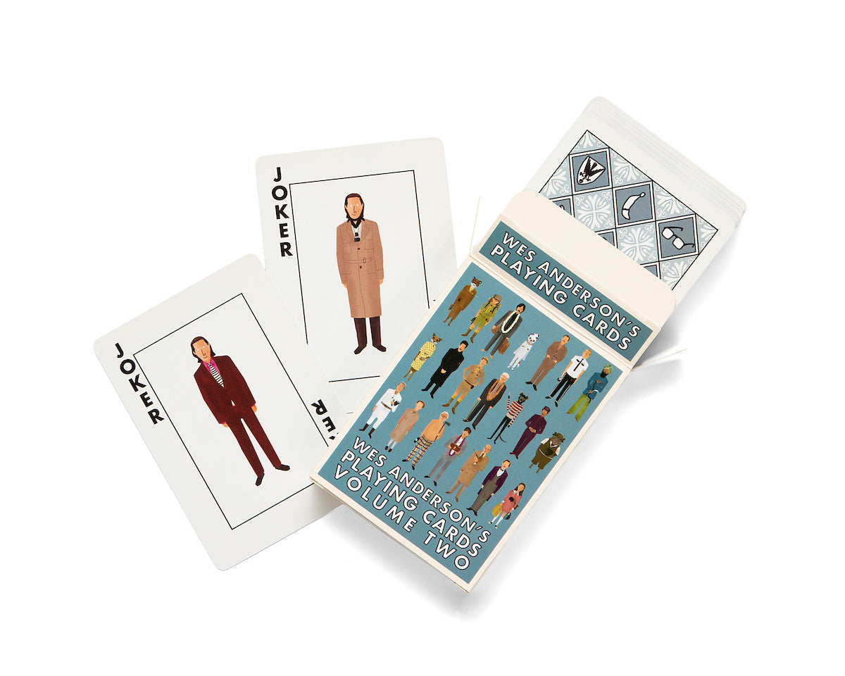 A deck of Max Dalton’s Playing Cards Volume Two features illustrated characters on the box and jokers, with artwork by Max Dalton. Two joker cards are displayed next to the partially open deck, revealing more custom designed playing cards inside.