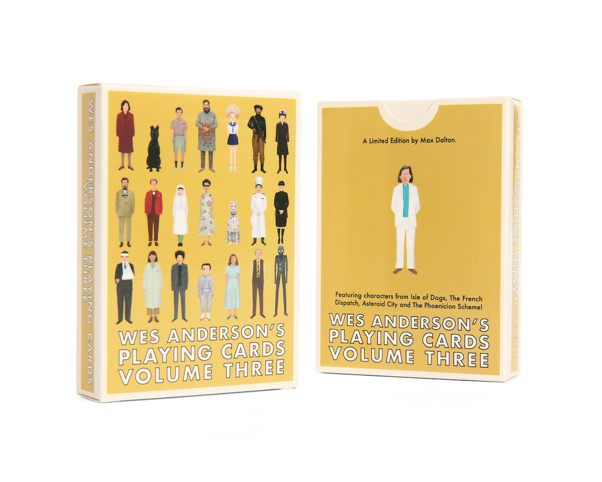 Two boxes of Max Dalton’s Playing Cards Volume Three stand side by side. The custom-designed playing cards come in yellow boxes adorned with illustrations of various characters in distinctive costumes from Wes Anderson films, all brought to life with artwork by Max Dalton.