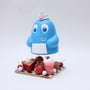A playful scene features a blue cartoon character with a white hat and an "INKY" tag by Zard Apuya, standing on a checkered platform among desserts, inspired by Pac Man video game art.