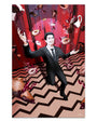 A joyful man in a suit poses on a zigzag floor as coffee cups, donuts, and cherry pie slices float around him against a red and black backdrop in Zi Xus archival pigment print, Cooper’s Dream.