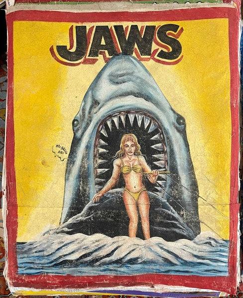 A vintage-style JAWS painting by Deadly Prey depicts a woman in a yellow bikini standing in water as a giant shark with an open mouth looms behind her; the background features bold yellow and red hues.