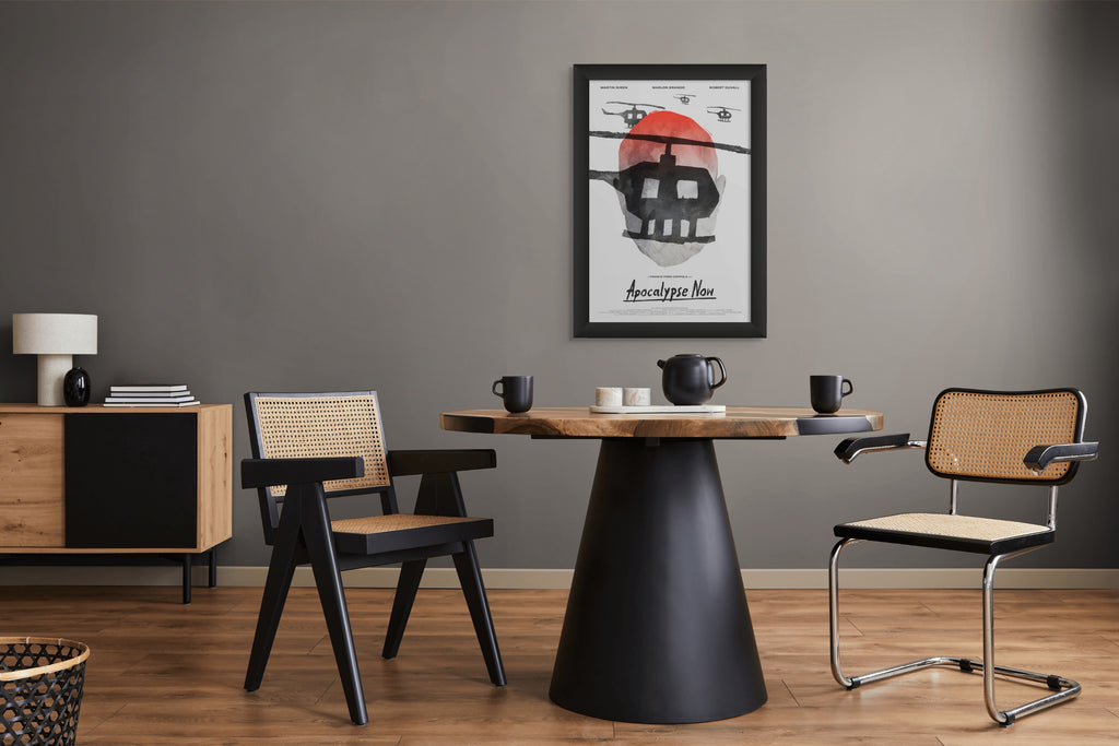 Photo of Aleksander Walijewski's Apocalupse Now print in a black frame on a gray wall in a dining room with a round table and chairs 
