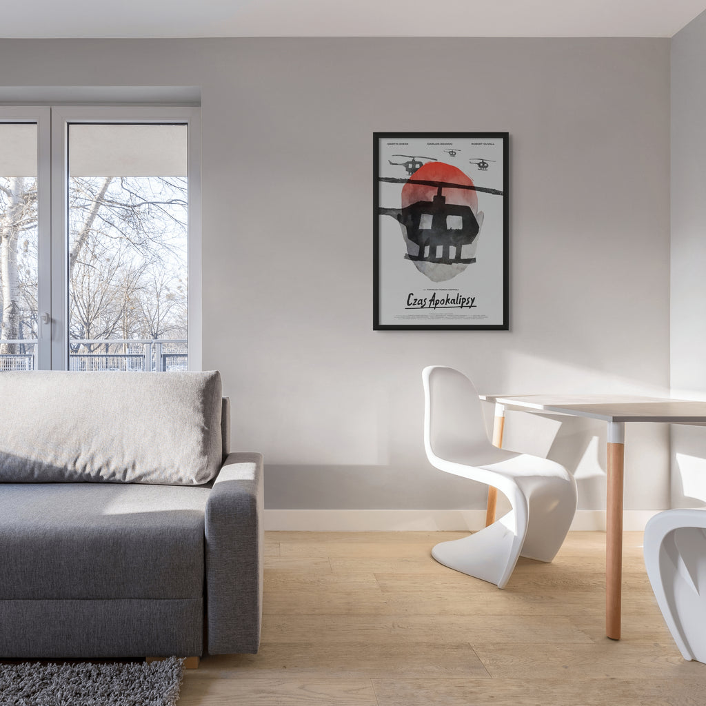 Photo of Aleksander Walijewski's Apocalupse Now print in a black frame on a gray wall in a living room with large windows. 