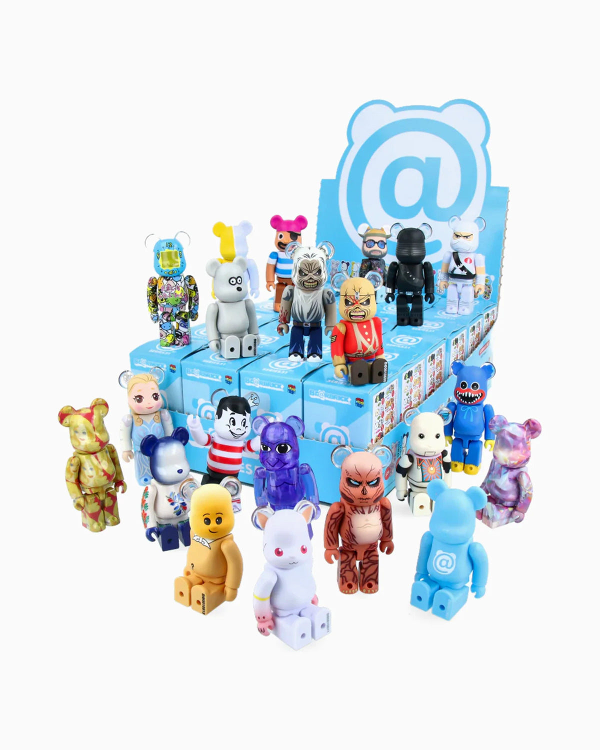 A display of vibrant bear-shaped collectible toys from Medicom, each featuring distinct designs and patterns, arranged on and in front of a blue stand topped with an @ symbol and cartoon bear face, reminiscent of a Be@rbrick blind box reveal.