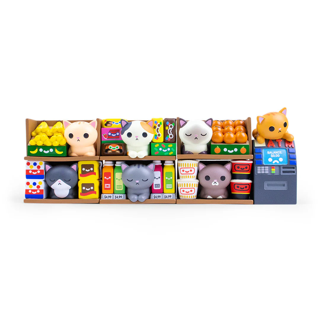 A toy supermarket shelf displays colorful mini food items with adorable 100% Soft Bodega Kitties cat figurines nestled among the goods, including an orange kitty perched atop a blue checkout counter. Experience the delightful charm of these 100% Soft vinyl figure blind box collectibles as they add playful personality to your miniature grocery scene.