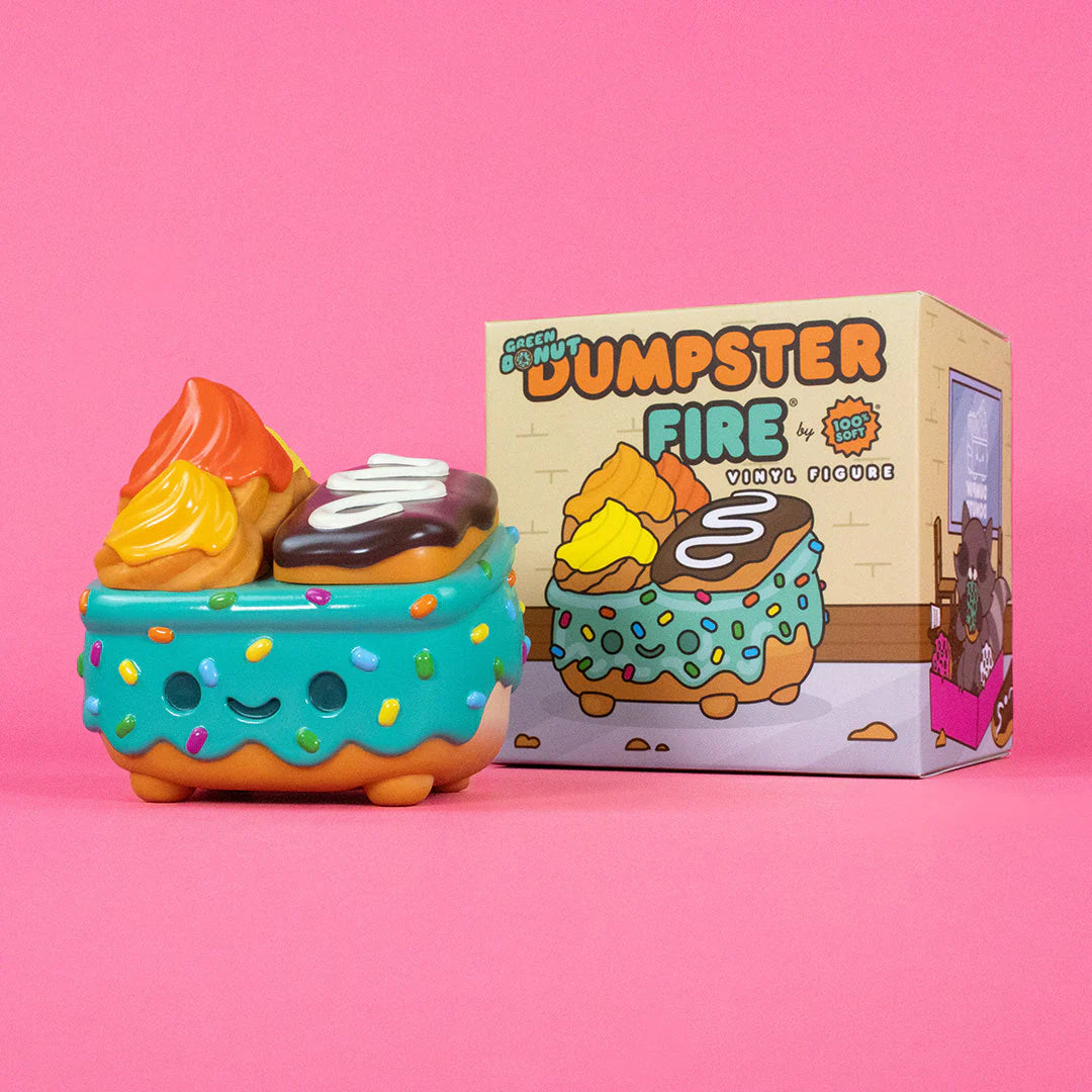A whimsical collectible from the 100% Soft Dumpster Fire collection, shaped like a decorated ice cream sundae in a blue dumpster with a smiling face and colorful sprinkles, sits beside its matching box against a pink background. This adorable toy captures all the charm that fans of 100% Soft love.