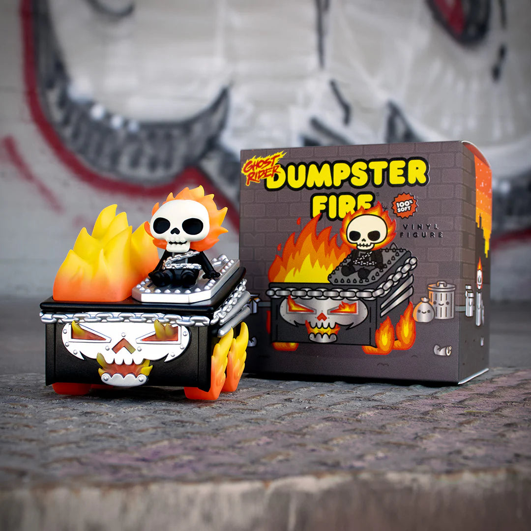A 100% Soft Ghost Rider Dumpster Fire vinyl figure showcasing a skeleton inspired by Marvel’s legendary antihero, seated in a blazing dumpster with bright orange and yellow flames. The packaging behind it features the matching bold image and reads “Dumpster Fire,” surrounded by playful cartoon flames and a graffiti-style background.