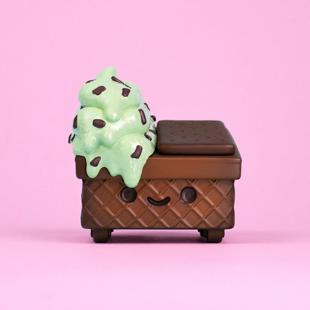 A toy shaped like an ice cream sandwich, topped with mint chocolate chip ice cream and a smiling face, set against a pink background—this adorable Mint Chip Vinyl Figure by 100% Soft is sure to sweeten any collection.