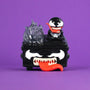 A black and white cartoonish Venom figure with a big red tongue and sharp teeth sits on a box featuring angry eyes, flames, and a smaller Venom on top, all set against a purple background—showcasing the fierce fun of the Marvel vinyl figure series in this unique 100% Soft Venom Dumpster Fire symbiote collectible.