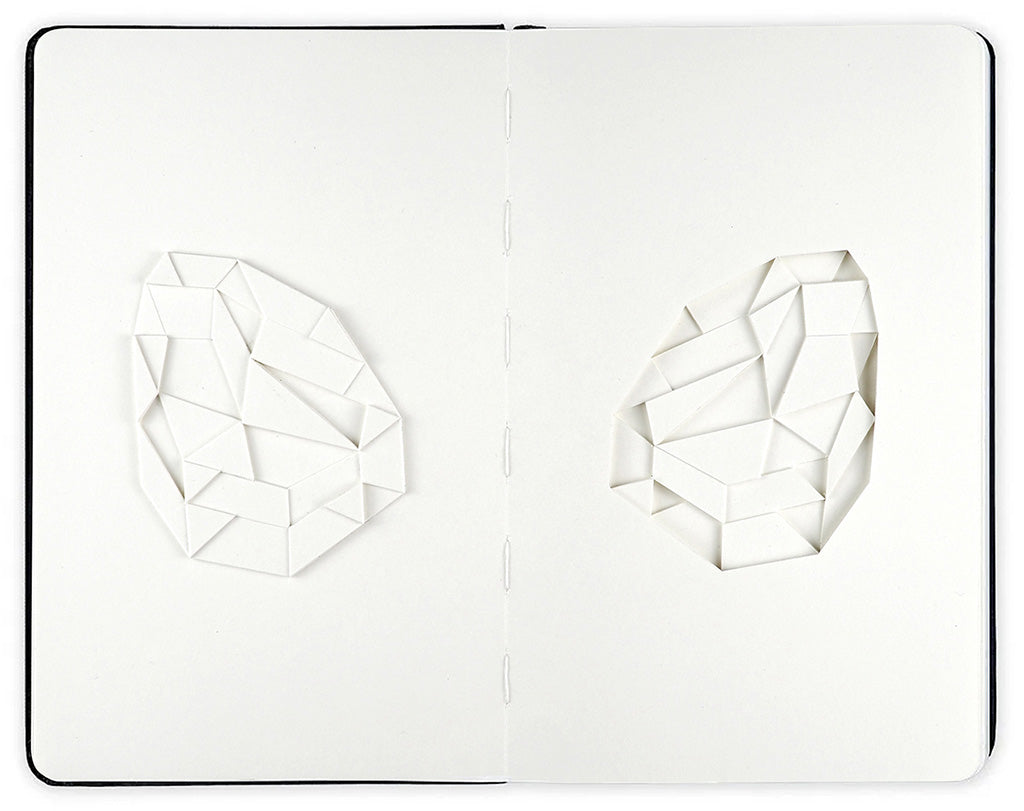 open face Moleskine notebook with cut geometric shapes on both pages by artist Huntz Liu