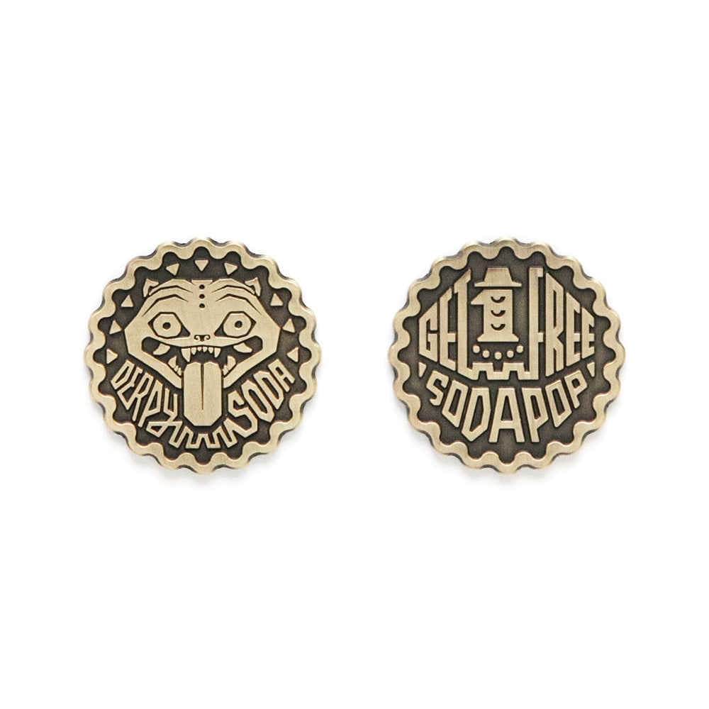 Two round tokens by Bruce Yan: one shows a cartoon face with its tongue out and says DERPY SODA; the other reads GET 1 FREE SODA POP with a bottle image—great additions to any Derpy Soda Token collection!.