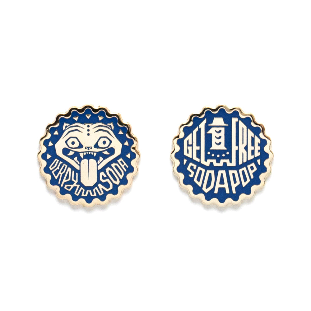Set of two blue and white enamel pins by Bruce Yan shaped like bottle caps—one with a cartoon face and "DERPY SODA" text, the other with "GET 1 FREE SODA POP." Fun collectible metal tokens for any Derpy Soda Token fan.