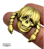 A brass-colored skull pin by ZOLTRON with a wide grin, braided pigtails, bangs, and the VOLTRON logo in the bottom left—this limited edition piece is true Zoltron art.