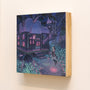Nicole Gustafssons gouache painting, mounted on a wooden block, depicts a whimsical scene of an enchanting cottage with glowing windows in a dark forest. A figure stands outside amid luminous ground patterns under a starry sky, creating an art gallery-worthy ethereal gleam.