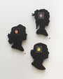 Three black silhouette profiles by Matt Ritchie, crafted from hand-cut wood, are wall-mounted and feature square electronic components at their centers. Acrylic textures highlight diverse hairstyles facing various directions, while small red dots add intrigue to this art gallery piece.