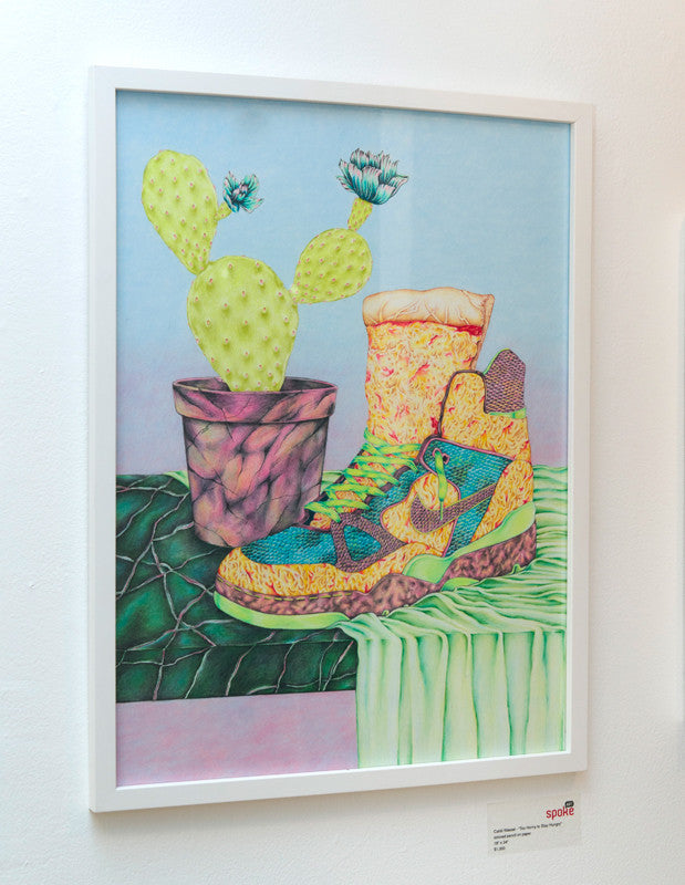 The Cahill Wessel sneaker, adorned with intricate pink, yellow, blue, and green patterns, is illustrated beside a potted cactus. This vibrant design evokes the theme Too Horny to Stay Hungry against a pastel blue gradient background and textured green surface.