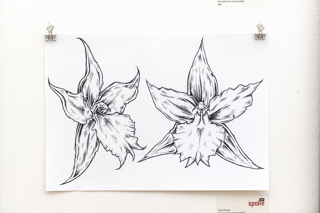 A black and white sketch of two stylized flowers with sharp, angular petals on a white sheet, akin to a Rhys Cooper preliminary drawing, clipped to a textured wall.