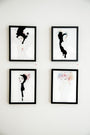 Four framed artworks on a white wall feature stylized female figures with abstract and floral elements. Each watercolor and India ink piece highlights unique hairstyles and poses. The minimalist color palette emphasizes black, white, and subtle pastels, echoing Conrad Rosets brand style.