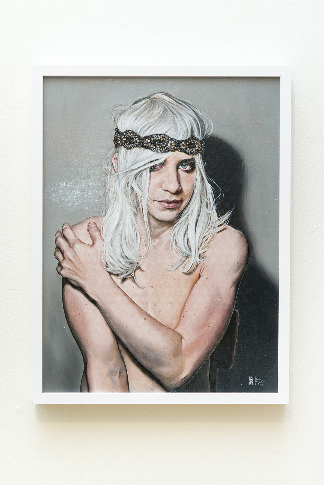 A Kaspian Shore framed painting shows a topless person with long white hair and a jeweled headband, seated against a plain background. They cross their arms over their chest and gaze at the viewer with an enigmatic expression, similar to the Boy with a Pearl Headband.