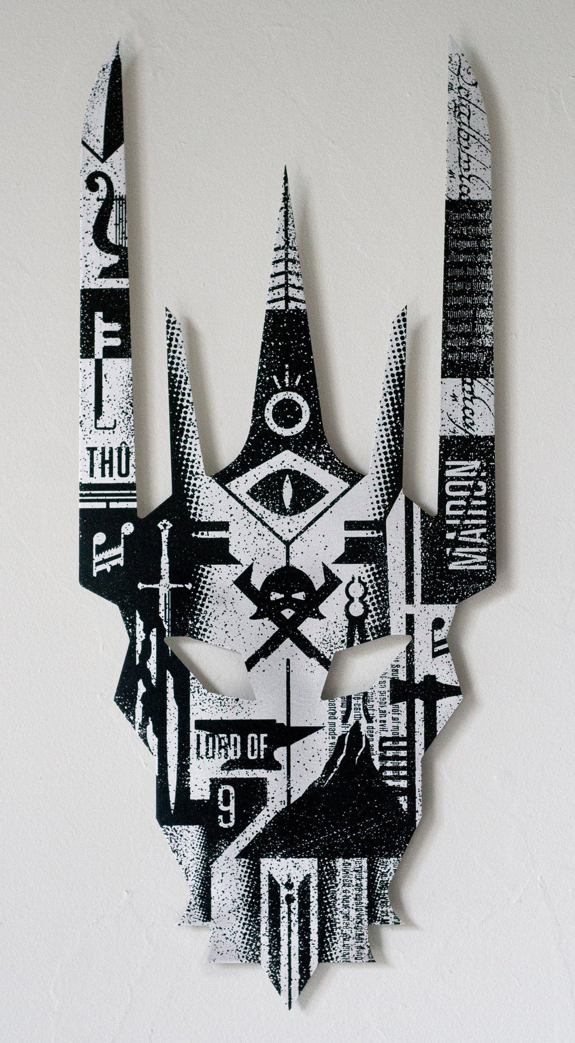 A Derek Ballard mask in black and white features intricate geometric patterns, symbols, an eye, and LORD OF 9 at the bottom. Elongated horn-like points give it a striking appearance reminiscent of The Dispensation of Sauron, showcased in screen ink on aluminum at Spoke Art Gallery.