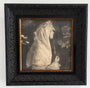 La Cura by Karla Ortiz is a black-and-white graphite on paper artwork in an ornate black frame. It features a person in a white headscarf and robe, gazing right, exuding an ethereal quality with soft lighting and blurred background details.