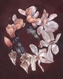 A circle of magnolia flowers, reflecting Jen Lobos style, forms against a dark backdrop. The blooms are white and pale pink with soft petals. Small green leaves and subtle textures enhance this enchanting arrangement.