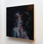 A white wall showcases an abstract Henrik Uldalen painting of a vague human form with swirling, mist-like textures. Soft pink and blue hues subtly emerge from the predominantly dark canvas, blending into the background like a supersonic flutter.