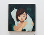 A young person with short brown hair cradles a white, cat-like creature in an UYU painting. Their serene gaze shines with sculpted iridescence against a dark, starry background—an entry for the Supersonic Invitational group show.