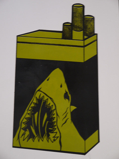 A fine art print creatively reimagines a cigarette pack as Shark Toofs open mouth, featuring sharp teeth and a rugged interior. The sharks body forms the pack, while cigarettes mimic smokestacks—an exquisite example of hand-printed artistry from Shark Toof.