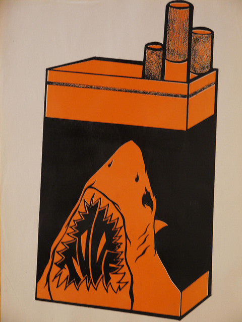 A cigarette pack illustration features a sharks head in vibrant orange and black, its open mouth replacing the front. This edgy hand-printed design is reminiscent of a Shark Toof paster.