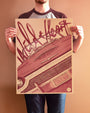 A person stands against a plain background wearing a raglan shirt and jeans while holding a Bartosz Kosowski-designed poster of Sailor and Lula in a vintage convertible. Printed on high-quality Popset paper, the vibrant poster features an illustration complete with a prominent signature across the top.