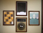 Four framed Jason Munn posters adorn the wall: top left features an abstract geometric pattern; top right displays a minimalist design with silhouettes on hills; bottom left showcases a circular nest with two eggs, signed by the artist; and bottom right contains abstract art with rose-like shapes in muted tones.