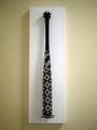 Lucien Shapiros Mixed Media collection features a woven black and white baseball bat on a vertical white plaque. The bat has a crisscross pattern, with small spikes on the knob, creating an Aurea Coronatus Spina Vespertilionem masterpiece.