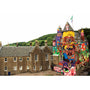 A historic building with traditional architecture is vibrantly painted in colorful urban art and murals. The artwork, echoing the Os Gemeos style, contrasts modern designs against the classic stone structure, while green hills in the background enhance this striking graffiti scene.