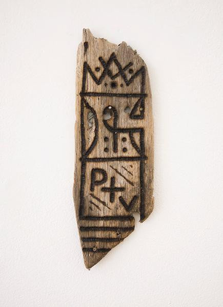 GATS presents a burnt driftwood art piece, adorned with abstract carvings of geometric shapes, lines, and symbols. Its rustic appearance contrasts beautifully against a white background.