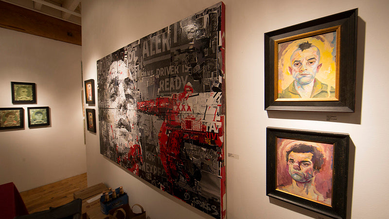 The Spoke Art gallery features a Derek Gores collage dominating one wall with vibrant reds and monochrome elements. Smaller expressive portraits with bold brushstrokes nearby capture attention, while warm lighting enhances the artworks details.