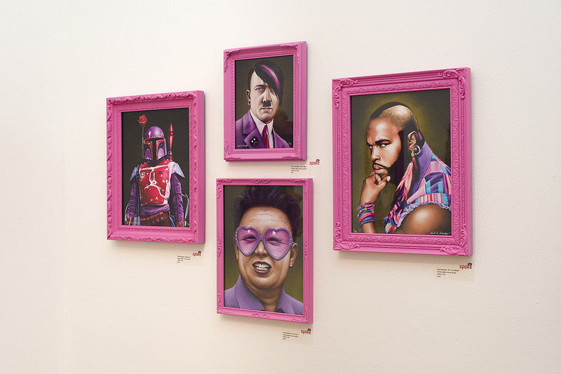 Four pop culture-inspired portraits, crafted as limited edition prints by Scott Scheidly, hang on the wall in pink frames. They feature a sci-fi character, a historical figure with pink hair, a man with a mohawk, and someone wearing heart-shaped glasses.