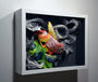 A Crystal Wagner-inspired shadow box art features an abstract 3D paper sculpture with intricate colorful loops in black, white, yellow, orange, green, and gray, enclosed in a white frame.